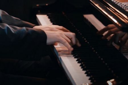 na zdjęciu widać dłonie na klawiaturze fortepianu